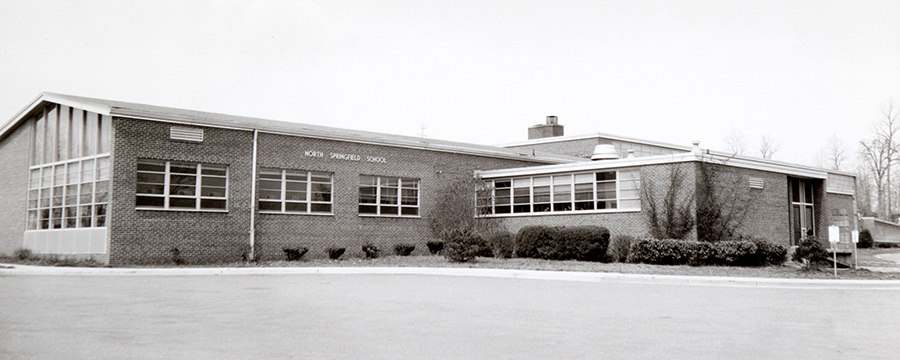 Black and white photograph of the front of North Springfield Elementary School taken in the 1960s. It appears to pre-date the color photograph shown later on this page because the shrubs in front of the building are smaller in size. 